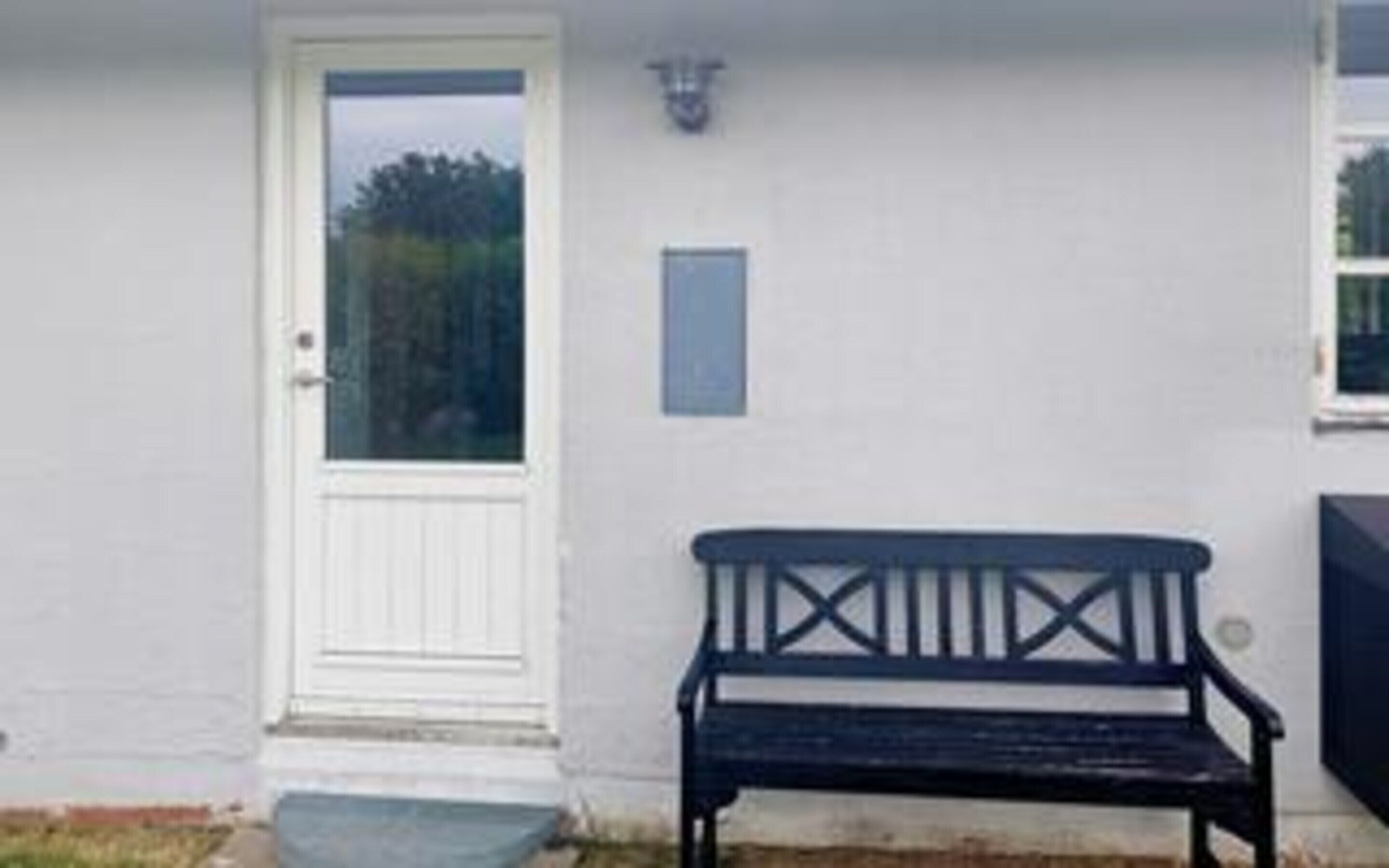 A white door with a glass panel, a bench, and a small plaque on the wall.