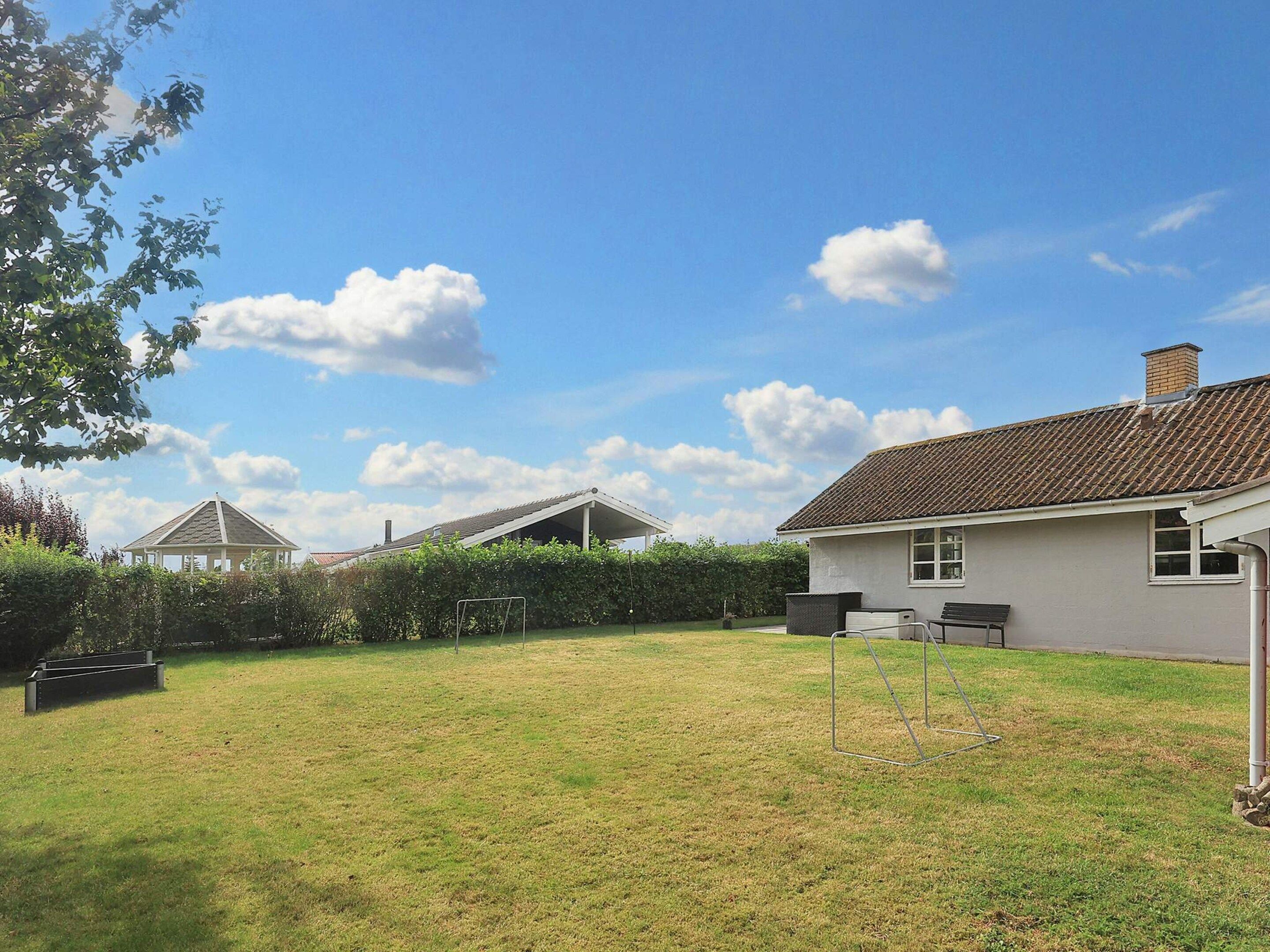 A residential property with a well-maintained lawn, a gazebo, and a house with a tiled roof.