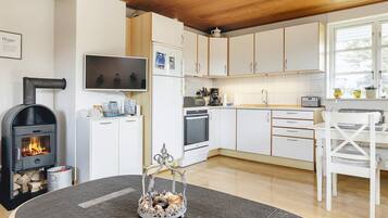 Een moderne keuken met witte kastjes, een ingebouwde oven, een fornuis en een eethoek met een witte tafel en stoelen.