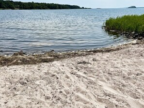 A sandy beach with water, vegetation, and distant land. - 4 Person Holiday Home in Morrum (Morrum)