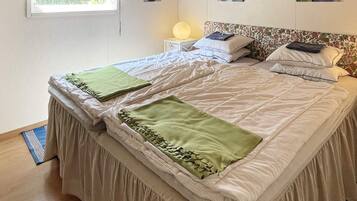 A neatly made bed with a green throw blanket and a headboard with a floral pattern.