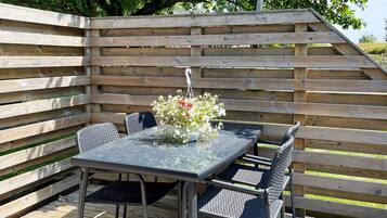 An outdoor patio with a table and chairs, surrounded by wooden slats.