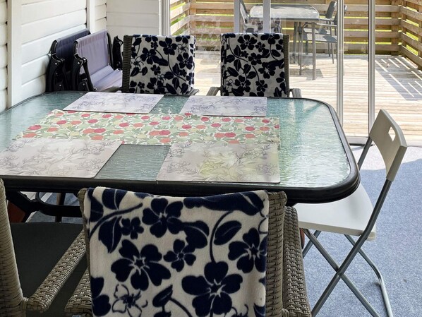 A glass-top table with floral tablecloths and wicker chairs with floral upholstery. - 4 Person Holiday Home in Morrum (Morrum)