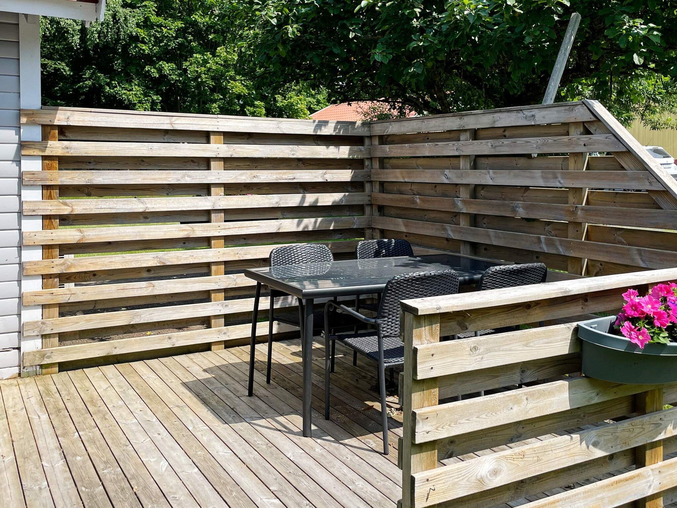 A wooden deck with a table and chairs, surrounded by a wooden fence.