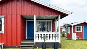 Punainen puinen rakennus, jossa on valkoinen kuisti ja sininen ovi.