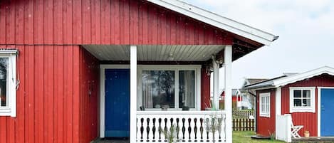 A red wooden building with a white porch and a blue door.