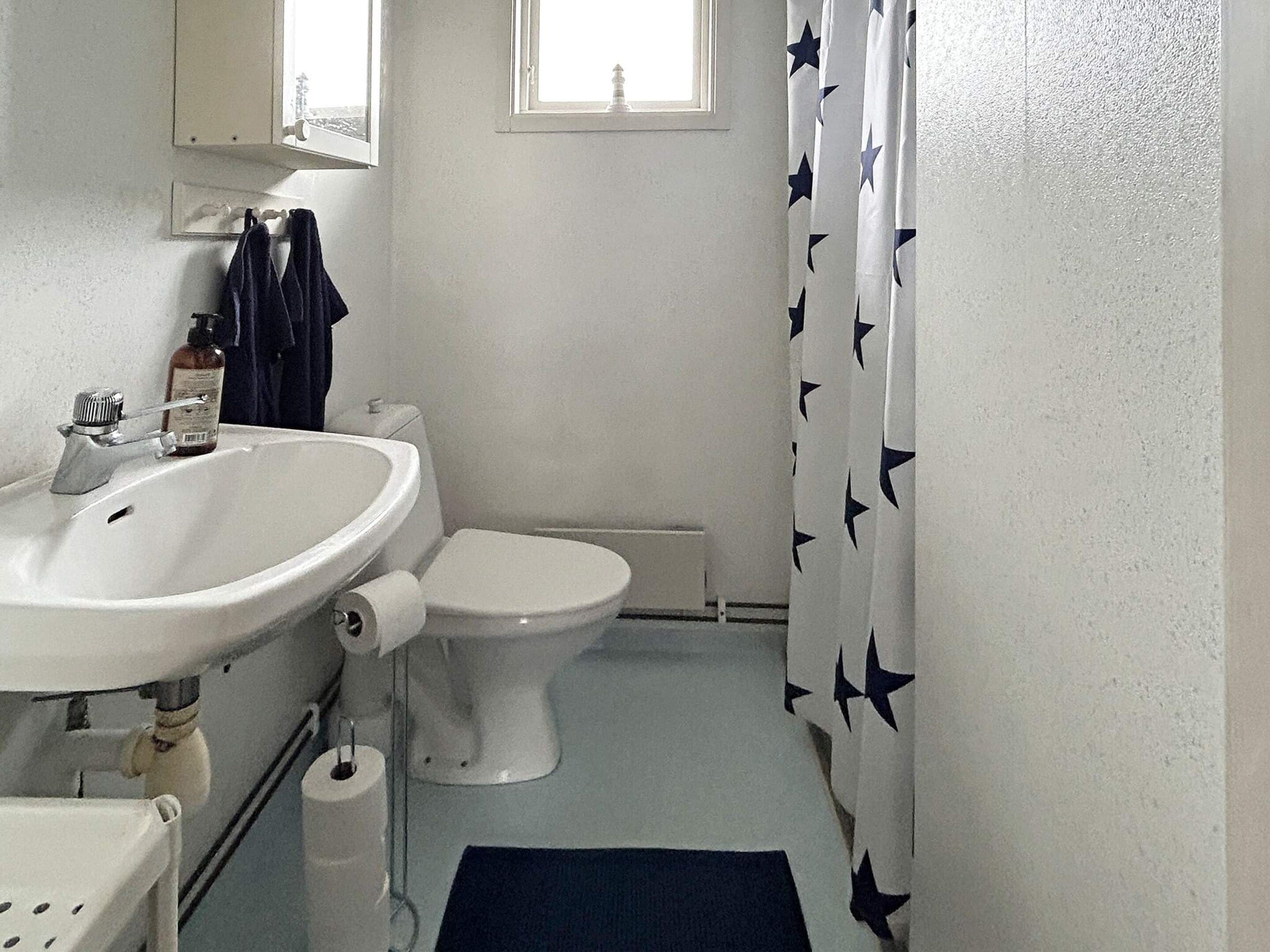 Ein Badezimmer mit weißem Waschbecken, WC und Duschvorhang mit Sternenmuster.