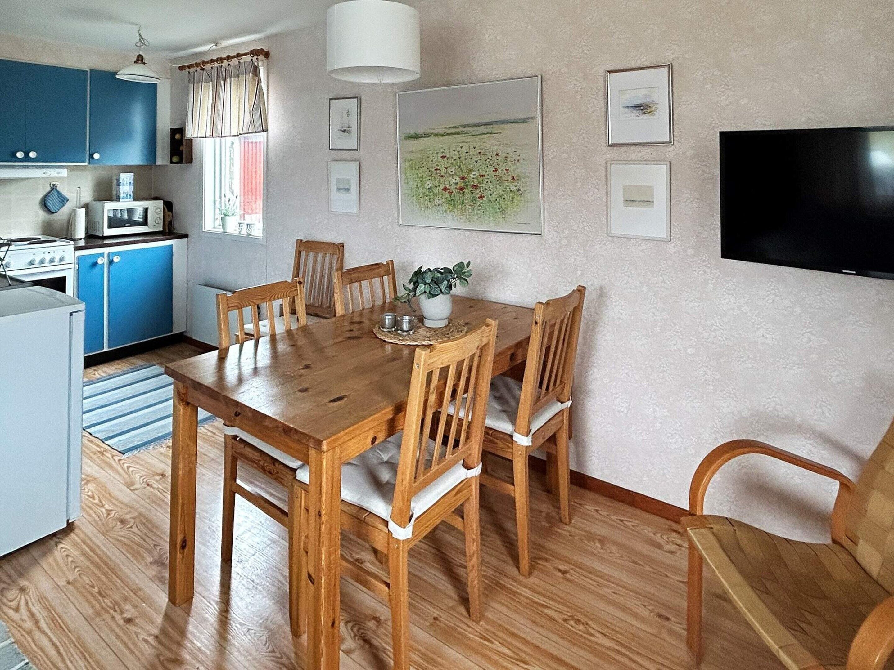 A dining area with a wooden table and chairs, a kitchen with blue cabinets, a microwave, and a stove.