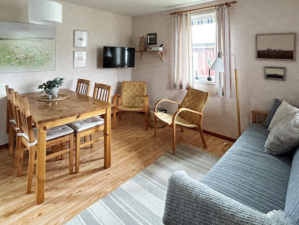 A cozy living room with a wooden dining table, chairs, a sofa, and a television. - 6 Person Holiday Home in Laholm (Skummesloevsstrand)
