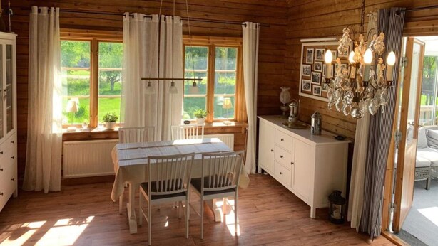 A wooden interior with a dining table, chairs, a white cabinet, and a chandelier. - 4 Star Holiday Home in Malmkoping (Malmkoping)