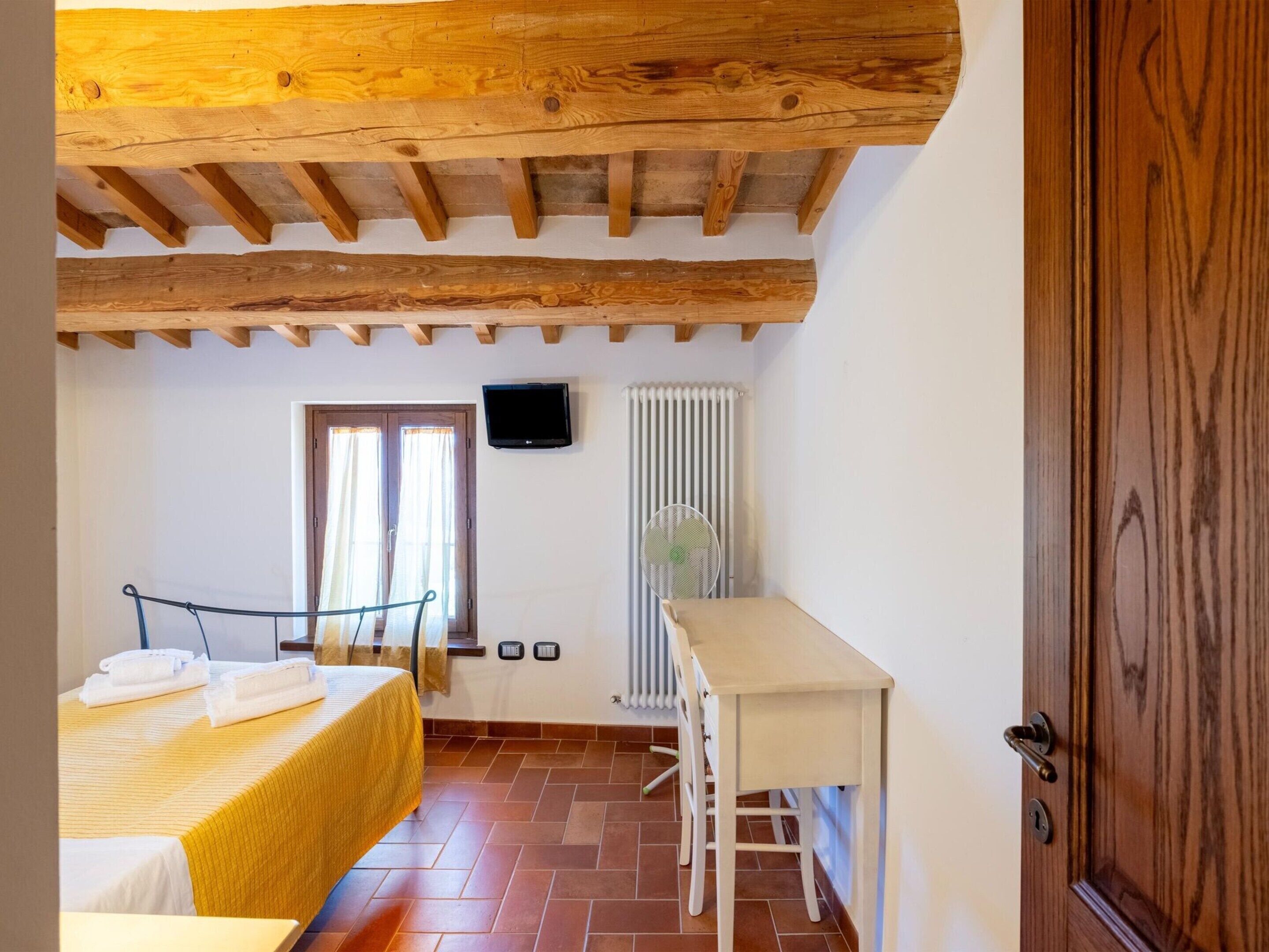 Une pièce avec un lit, une table, un radiateur et une porte.