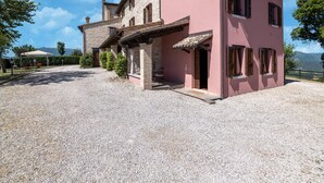 A two-story house with a gravel driveway and a covered patio area. - Relaxing Countryside Stay (Cagli)