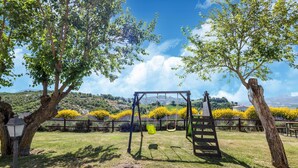 A park with a swing set, trees, and a view of distant hills. - Relaxing Countryside Stay (Cagli)