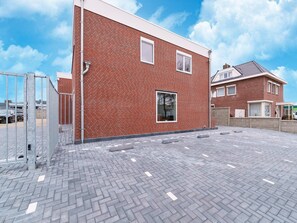 A modern two-story brick house with a paved driveway and a metal gate. - Serene Stay With All You Need (Landgraaf)