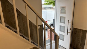 A staircase with wooden paneling and a white door with frosted glass panels. - Serene Stay With All You Need (Landgraaf)