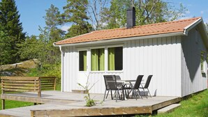 A small cabin with a deck, a table with chairs, and a bench. - 5 Person Holiday Home in Stromstad (Stromstad)