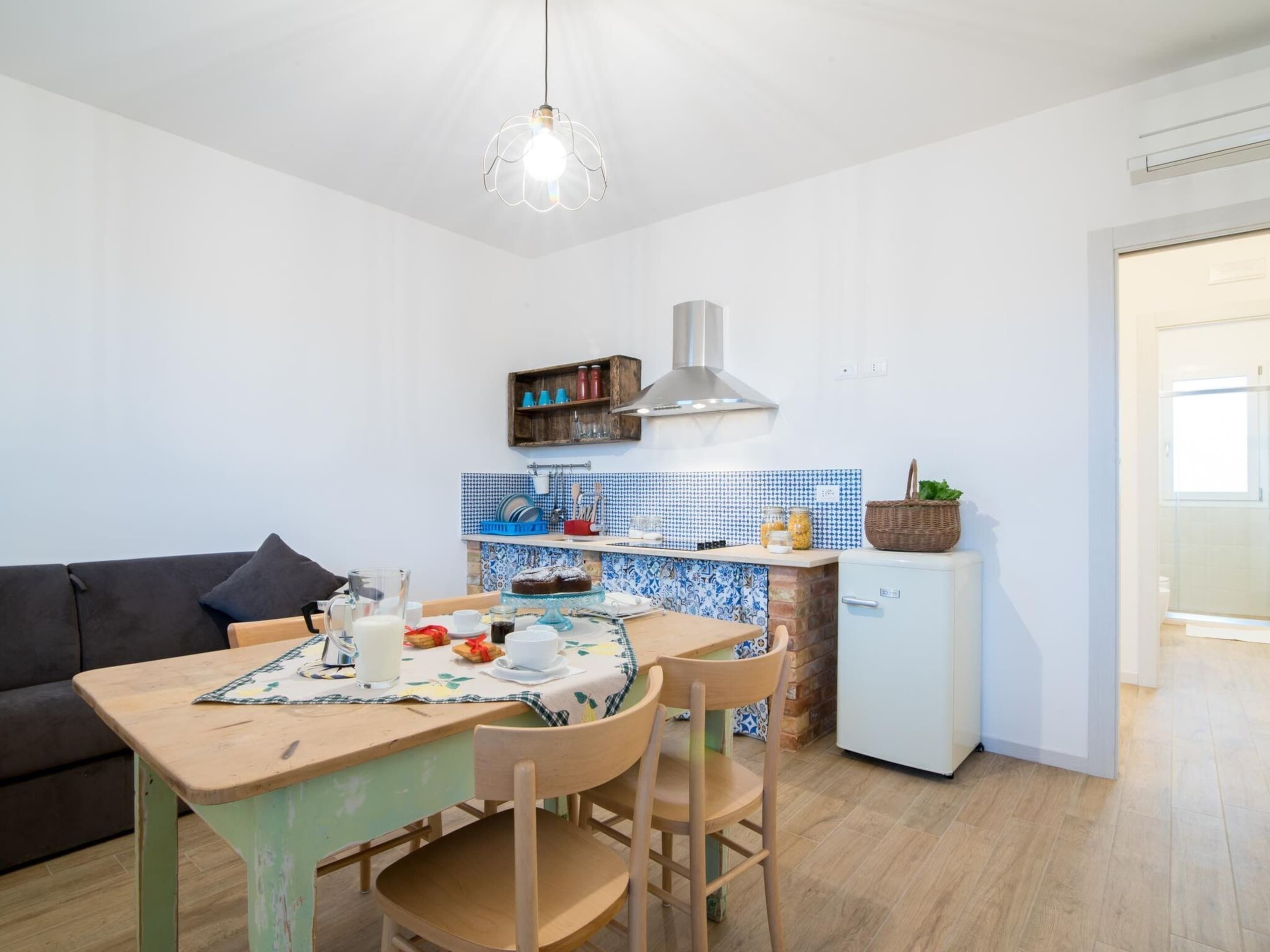 A compact kitchen with a dining table, chairs, and a refrigerator.