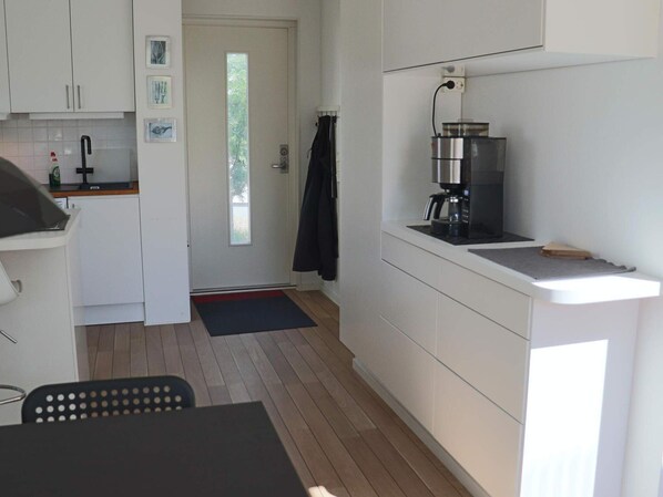 A modern kitchen with white cabinets, a coffee machine, and a wooden floor. - 4 Star Holiday Home in Mellbystrand (Mellbystrand)