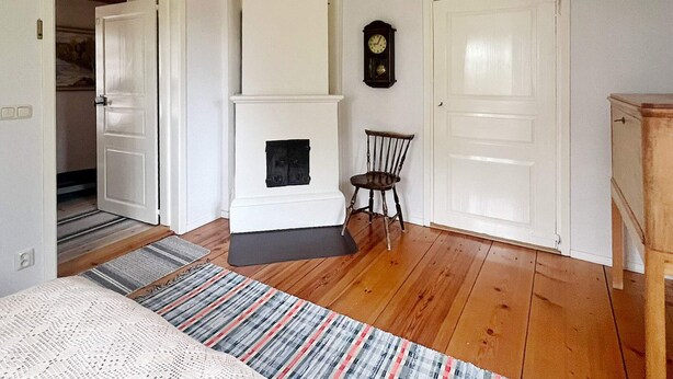 A room with a fireplace, a clock on the wall, and a door leading to another room. - 5 Person Holiday Home in Mariannelund (Mariannelund)