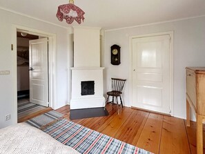 A room with a fireplace, a clock on the wall, and a door leading to another room. - 5 Person Holiday Home in Mariannelund (Mariannelund)