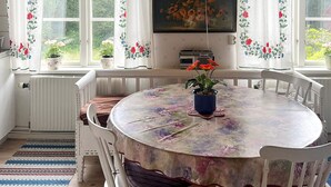 A dining area with a round table, chairs, a potted plant, and a window with curtains. - 5 Person Holiday Home in Mariannelund (Mariannelund)