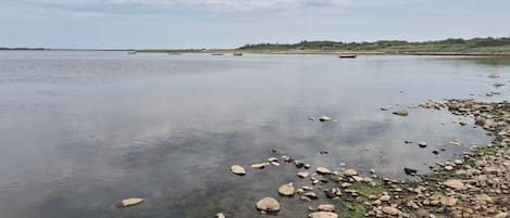 A calm lake with a rocky shoreline and boats in the distance.