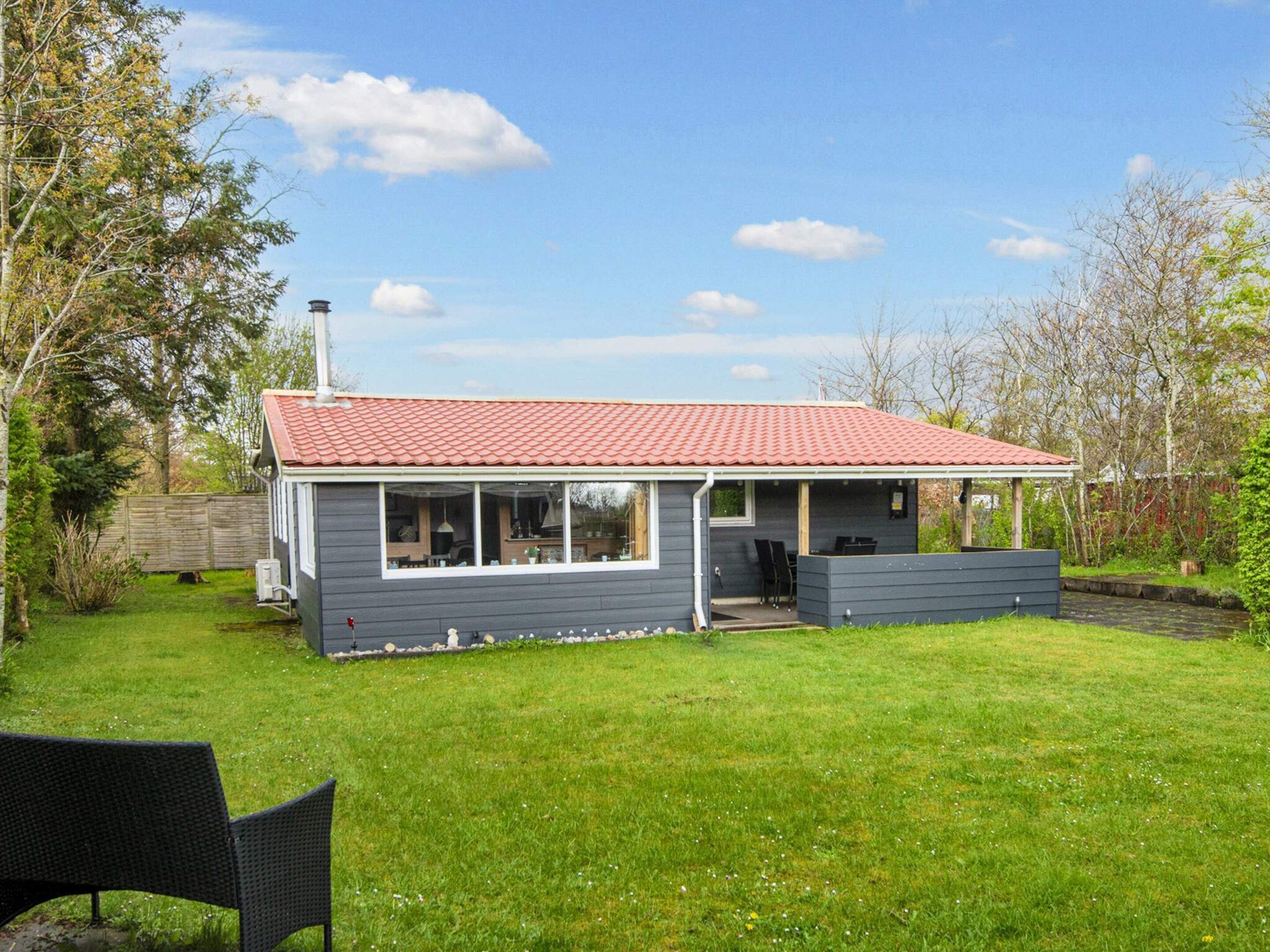 A single-story house with a red-tiled roof, a covered porch, and a small front yard.