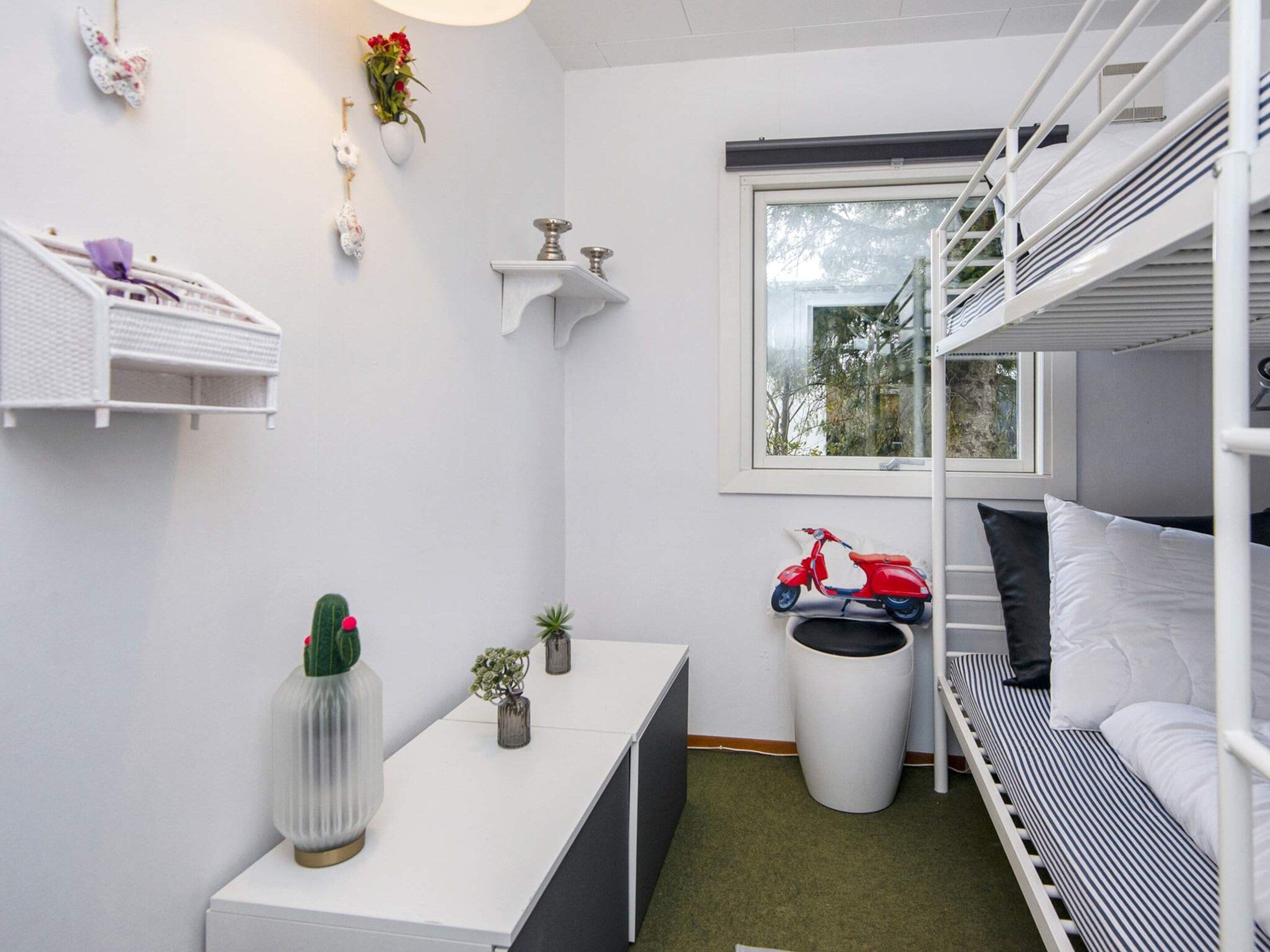 Habitación compacta y bien organizada con literas, un escritorio pequeño y una ventana con vistas al exterior.
