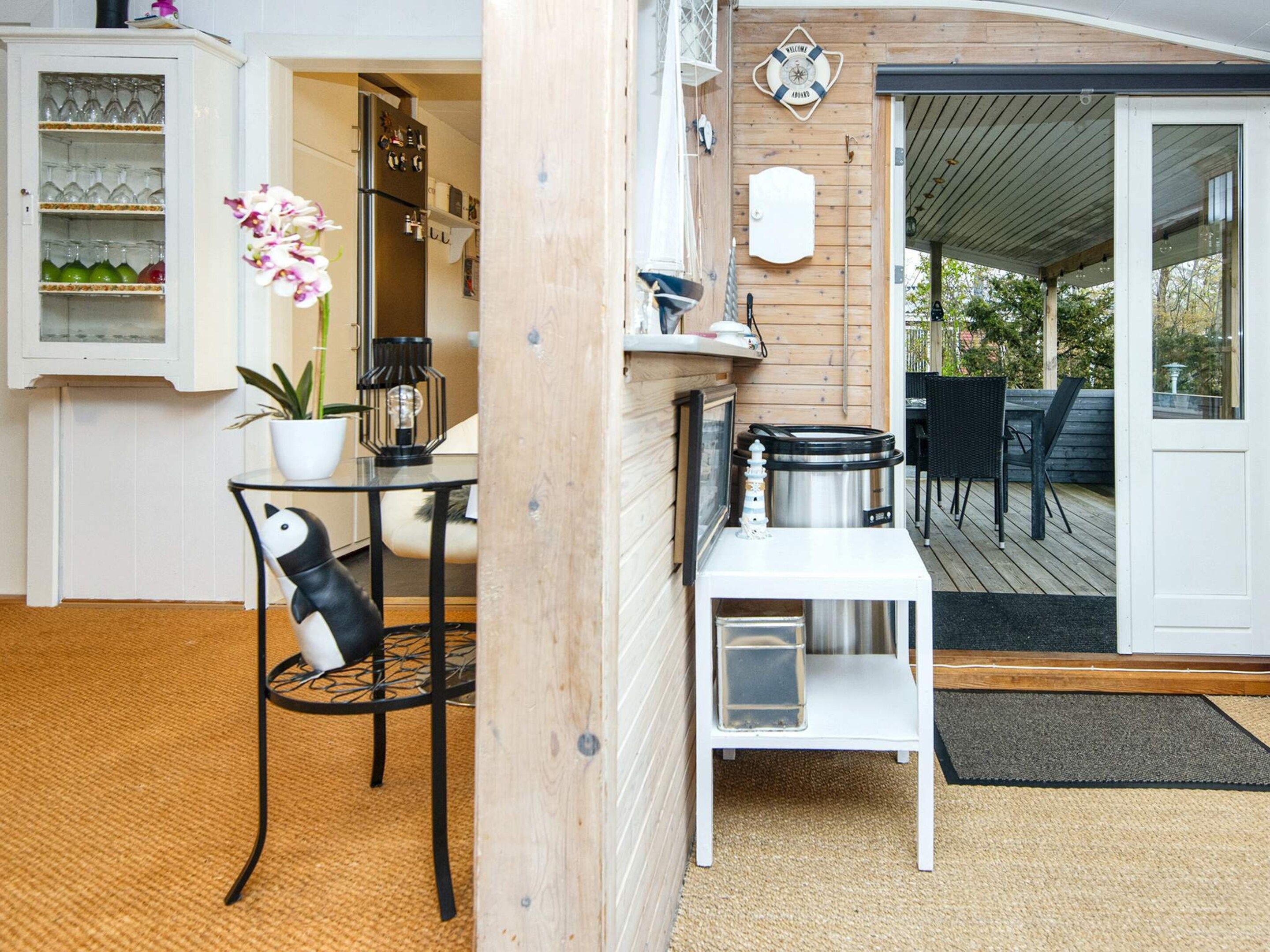 Een moderne keuken met een koelkast, een wit kastje met glazen, een eettafel met stoelen en een kleine witte tafel met een waterkoker.