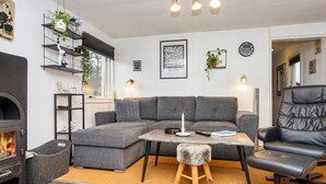 A cozy living room with a sectional sofa, a fireplace, a wooden coffee table, and a black leather armchair. - 5 Person Holiday Home in Tarm (Tarm)