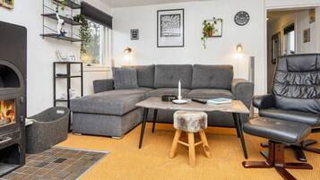 Uma sala de estar aconchegante com sofá seccional, lareira, mesa de centro de madeira e poltrona de couro preta.