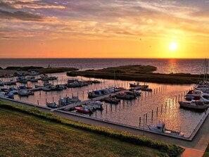 Un puerto deportivo con barcos amarrados, un muelle y un atardecer sobre el agua.