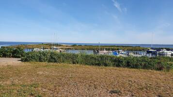 Un puerto deportivo con barcos amarrados, un primer plano con césped y un cielo despejado.