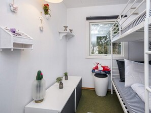 Una habitación pequeña con literas, una mesita, un ventanal y un coche de juguete rojo.