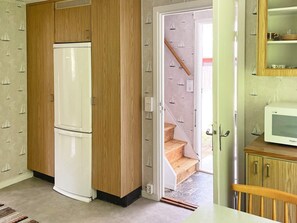 A compact kitchen with a white refrigerator, wooden cabinets, and a microwave on a wooden counter. - 4 Person Holiday Home in Asarum (Asarum)