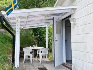 A covered patio with a table and chairs, a flag, and a door leading to a house. - 4 Person Holiday Home in Asarum (Asarum)