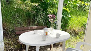 A white outdoor table with a bench, surrounded by greenery and a stone wall. - 4 Person Holiday Home in Asarum (Asarum)
