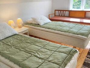 A room with two beds, a nightstand with lamps, and a window with a view of trees. - 4 Person Holiday Home in Asarum (Asarum)