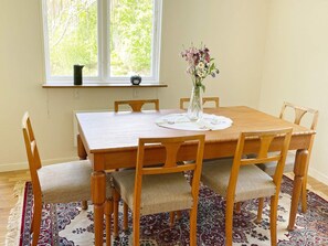 A dining table with six chairs, a vase with flowers, and a window with a view of trees. - 4 Person Holiday Home in Asarum (Asarum)