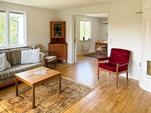 A living room with a sofa, a red chair, a wooden coffee table, and a patterned rug. - 4 Person Holiday Home in Asarum (Asarum)
