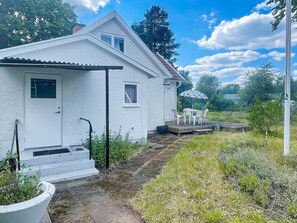 A white house with a front door, a small porch, and a table with chairs outside. - 5 Person Holiday Home in Bockara (Bockara)