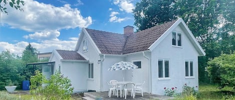 Una casa de dos pisos con un porche cubierto y una pequeña terraza.