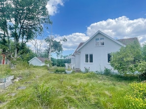 A white house with a sloped roof, surrounded by greenery and a clear sky. - 5 Person Holiday Home in Bockara (Bockara)