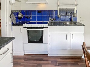 Une cuisine équipée d’une cuisinière, d’un four, d’un évier et d’un plan de travail bleu.