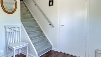 A staircase leading to a door, a white chair, and a wooden-framed mirror.