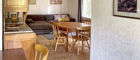 A compact living space with a dining area, a sofa, and a kitchen counter.