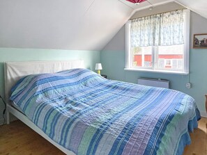 A single bed with a striped bedspread in a room with a sloped ceiling and a window with a curtain. - 5 Person Holiday Home in Bockara (Bockara)