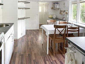 A kitchen with a dining area, wooden flooring, and a window with a view. - 5 Person Holiday Home in Bockara (Bockara)