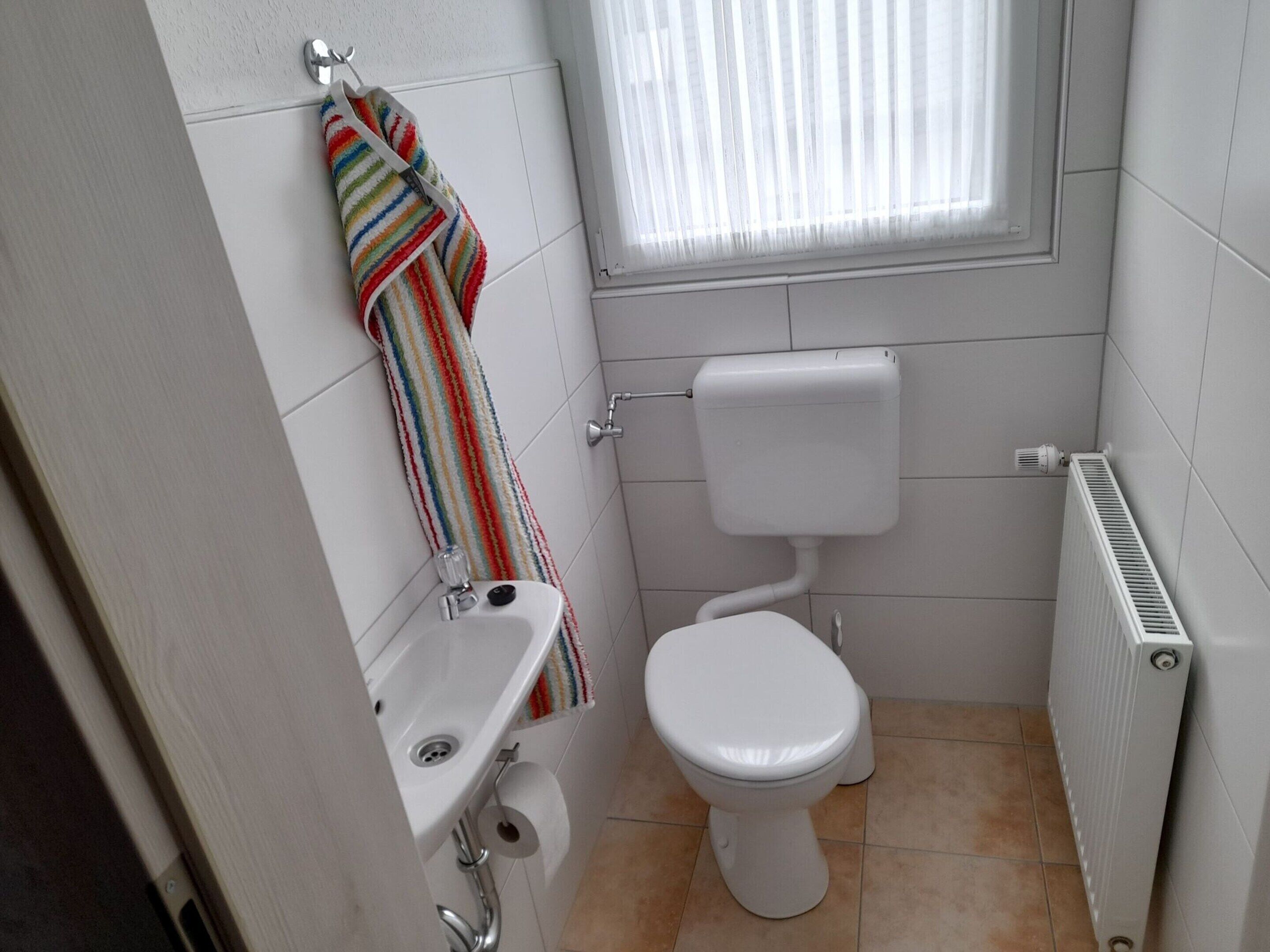 A small, clean bathroom with a toilet, sink, and window.
