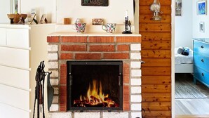 A cozy living room with a brick fireplace, wooden paneling, and a blue dresser. - 5 Person Holiday Home in Sodertalje (Sodertalje)